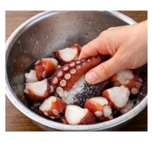 ボウルの中でタコを塩でもみ、ぬめりを取っている下処理の様子。